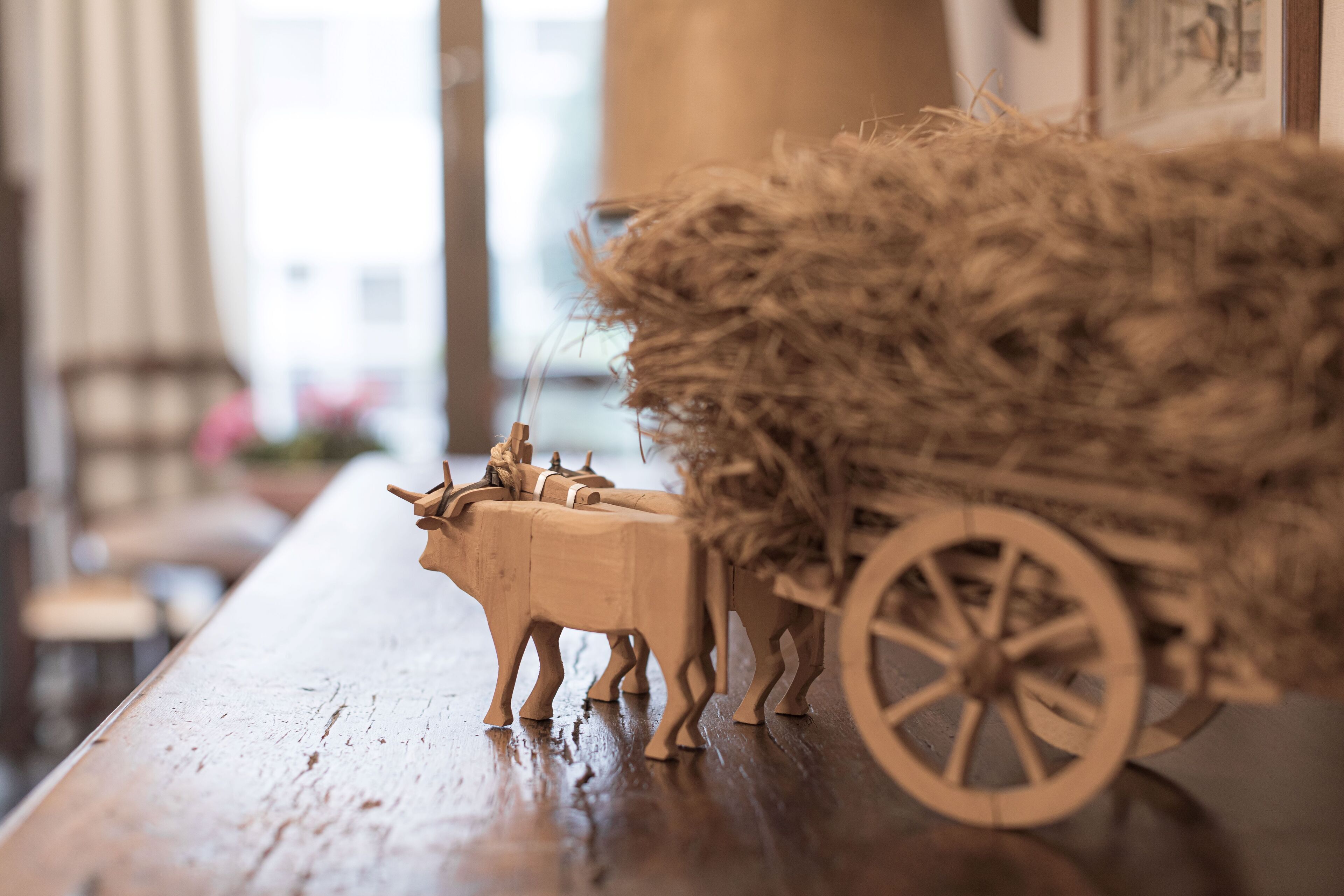 Un cheval en bois, jouet, tirant une charrette remplie de foin.