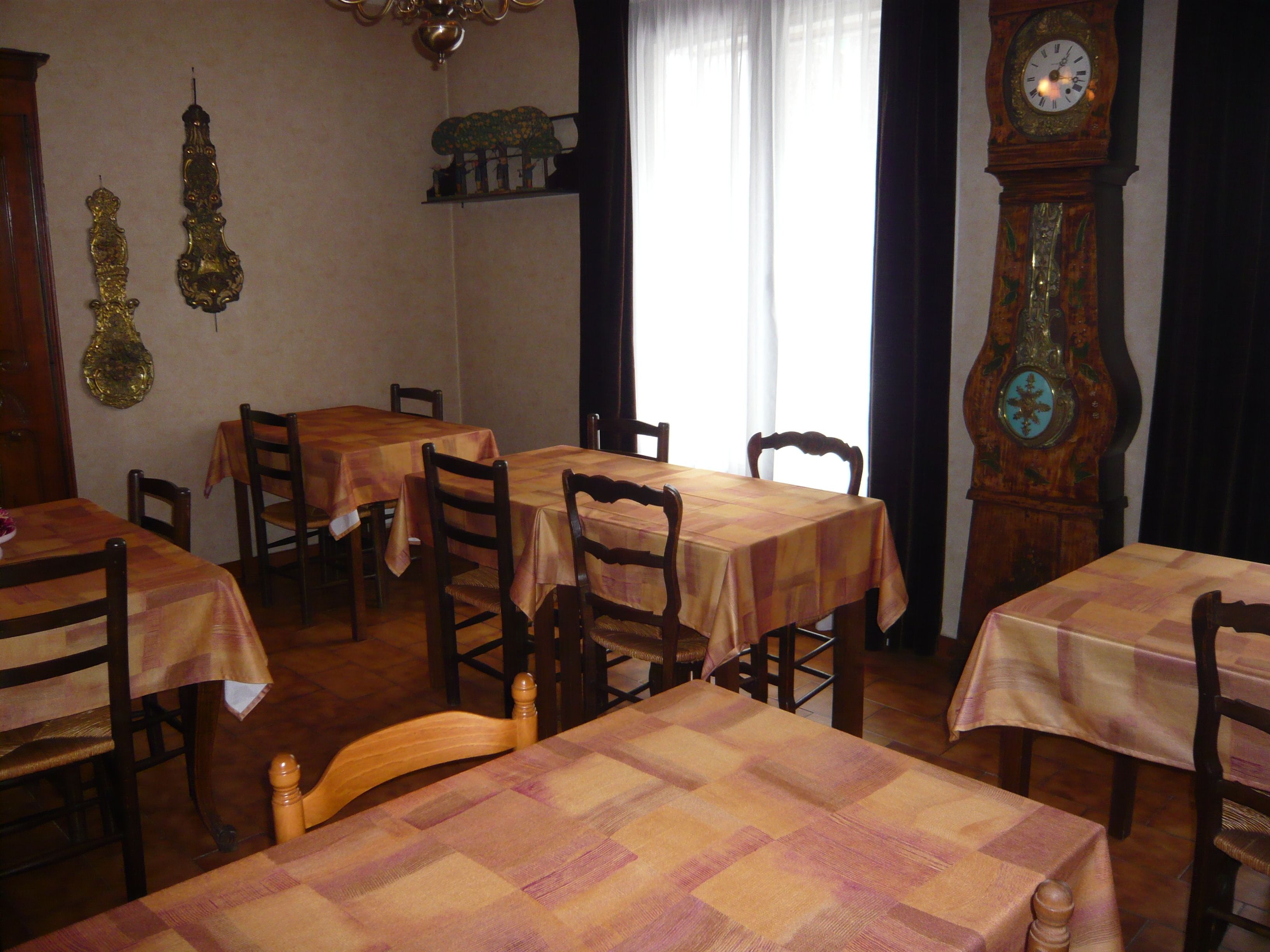 Zona pranzo con diversi tavoli e sedie, un grande orologio di legno e decorazioni a parete.
