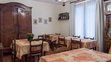 A dining area with multiple tables and chairs, a wooden cabinet, and a chandelier.