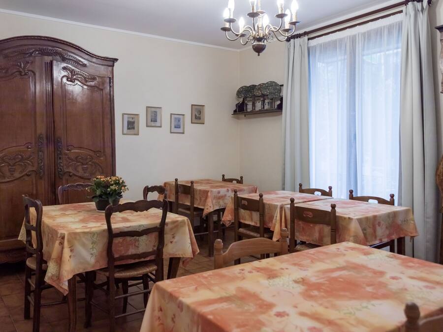 A dining area with multiple tables and chairs, a wooden cabinet, and a chandelier.
