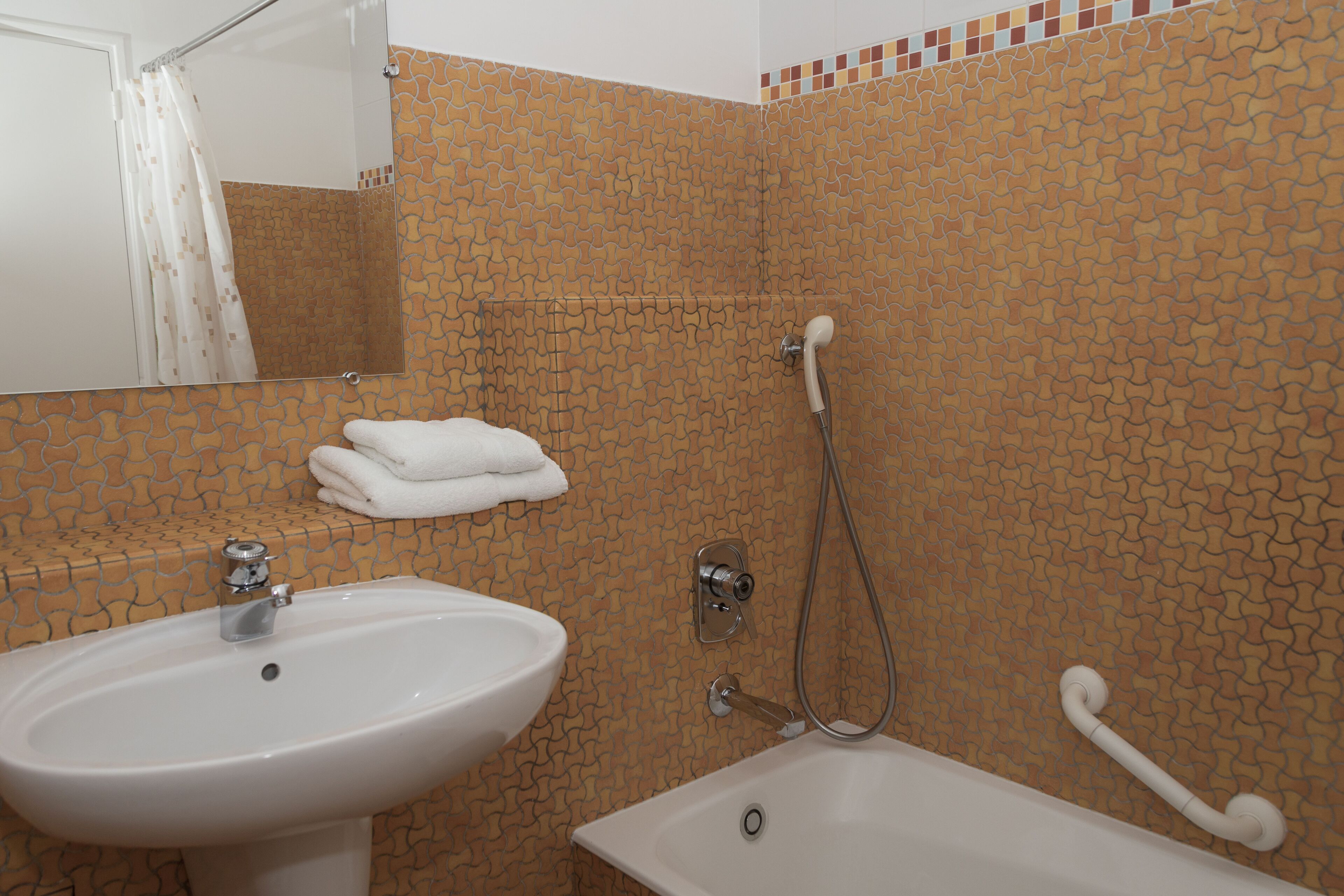 Une salle de bain équipée d’un lavabo, d’un miroir, d’une douche et d’un porte-serviettes.