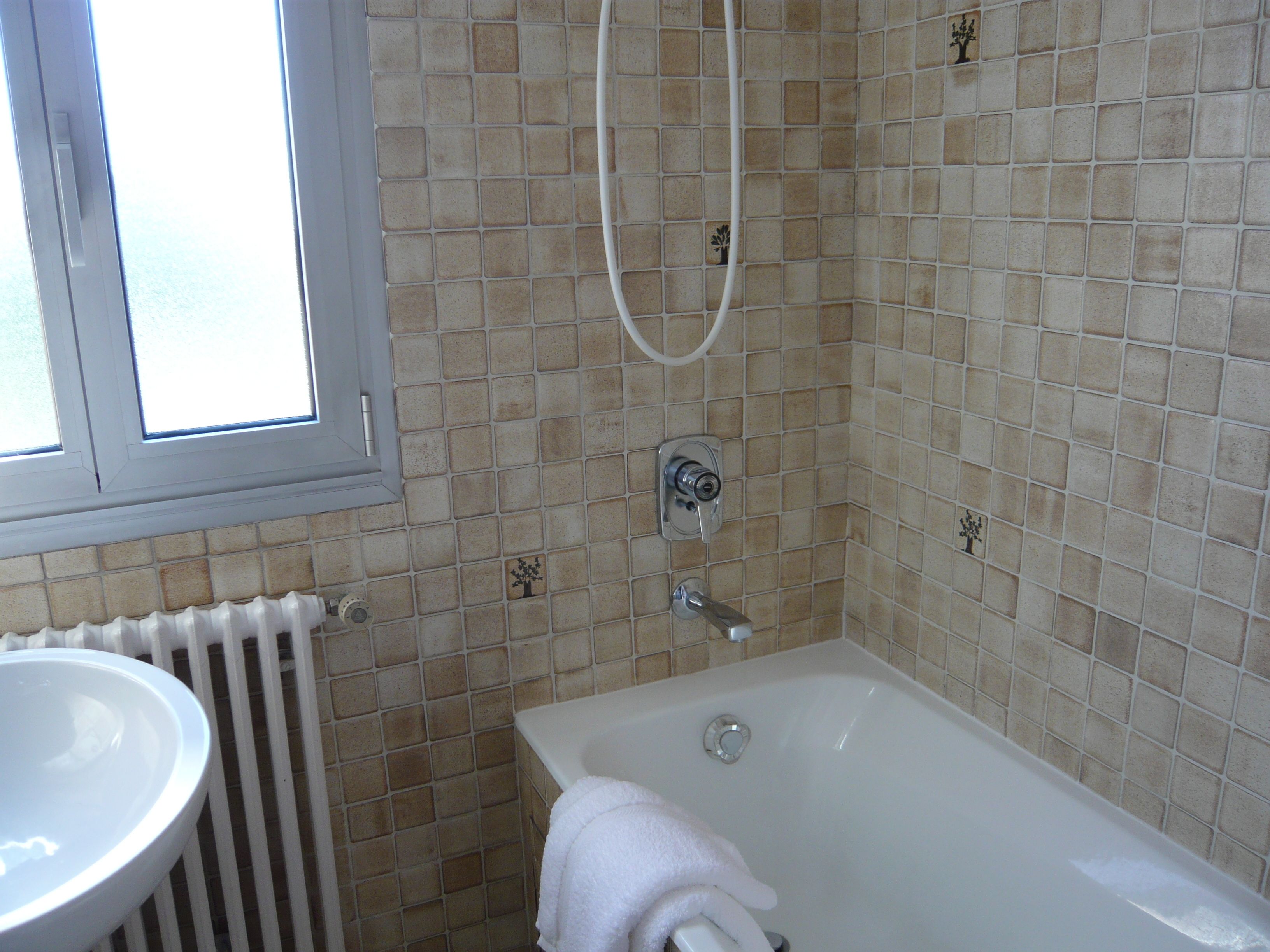 A bathroom with a bathtub, a window, and a radiator.