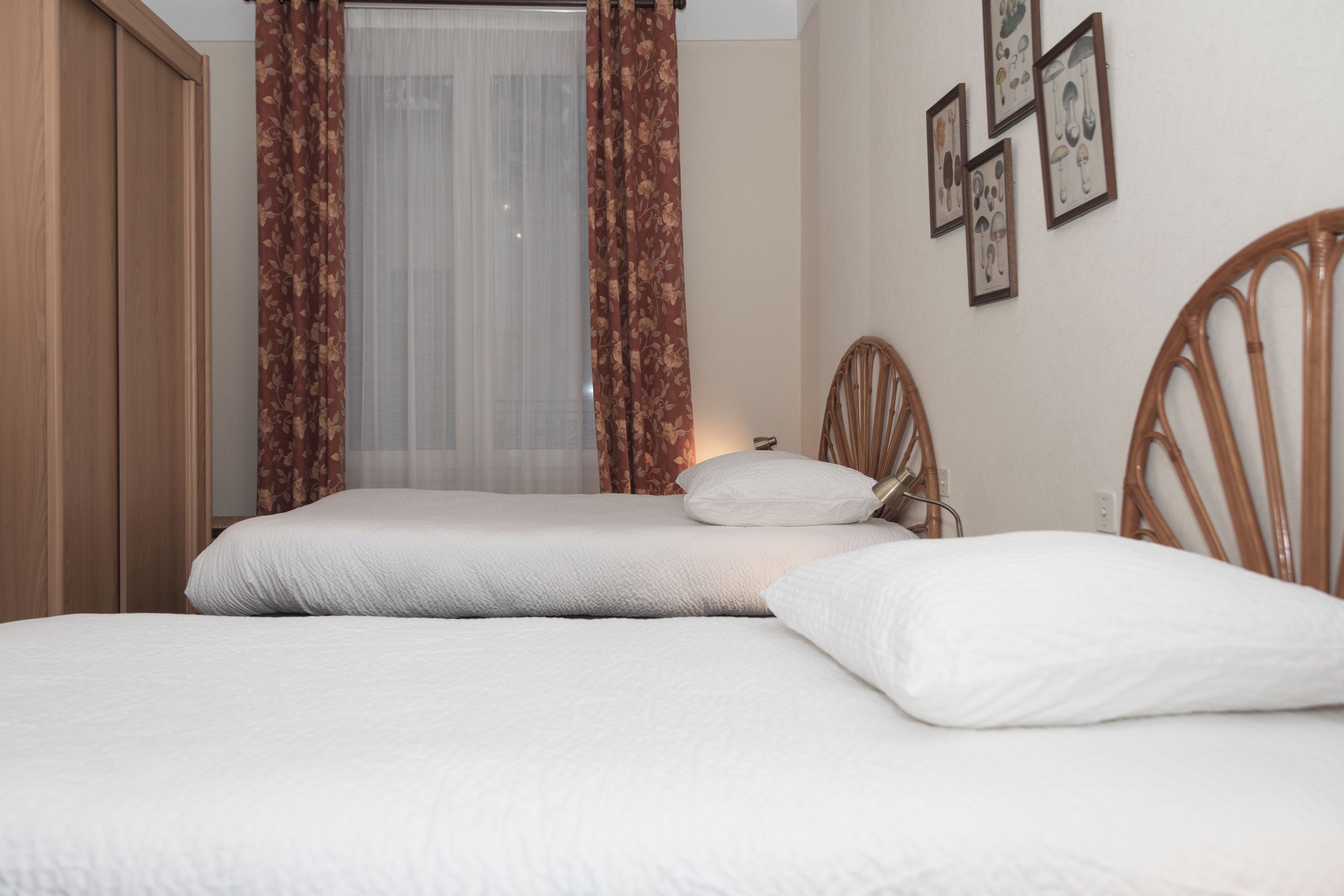 Una cama bien hecha con ropa de cama blanca en una habitación con muebles de madera y una ventana con cortinas translúcidas.