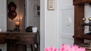 A dining area with a wooden table and chairs, a potted plant, and a wall-mounted lamp. - Citotel Aero Hotel (Le Blanc-Mesnil)
