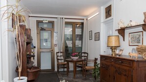 A room with a wooden cabinet, a table with chairs, a potted plant, and a door leading outside. - Citotel Aero Hotel (Le Blanc-Mesnil)