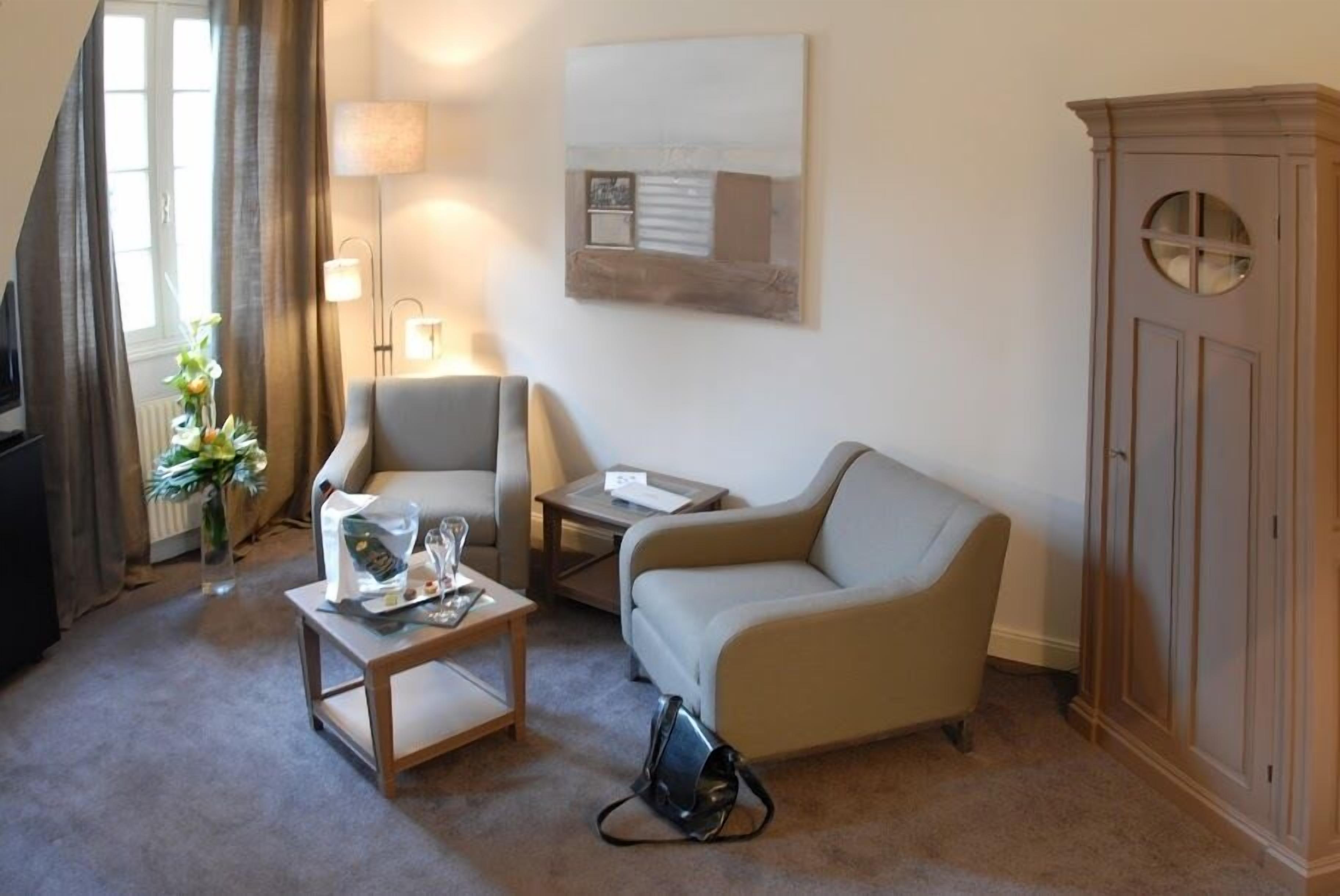 A living room with a sofa, armchair, coffee table, lamp, and a cabinet.