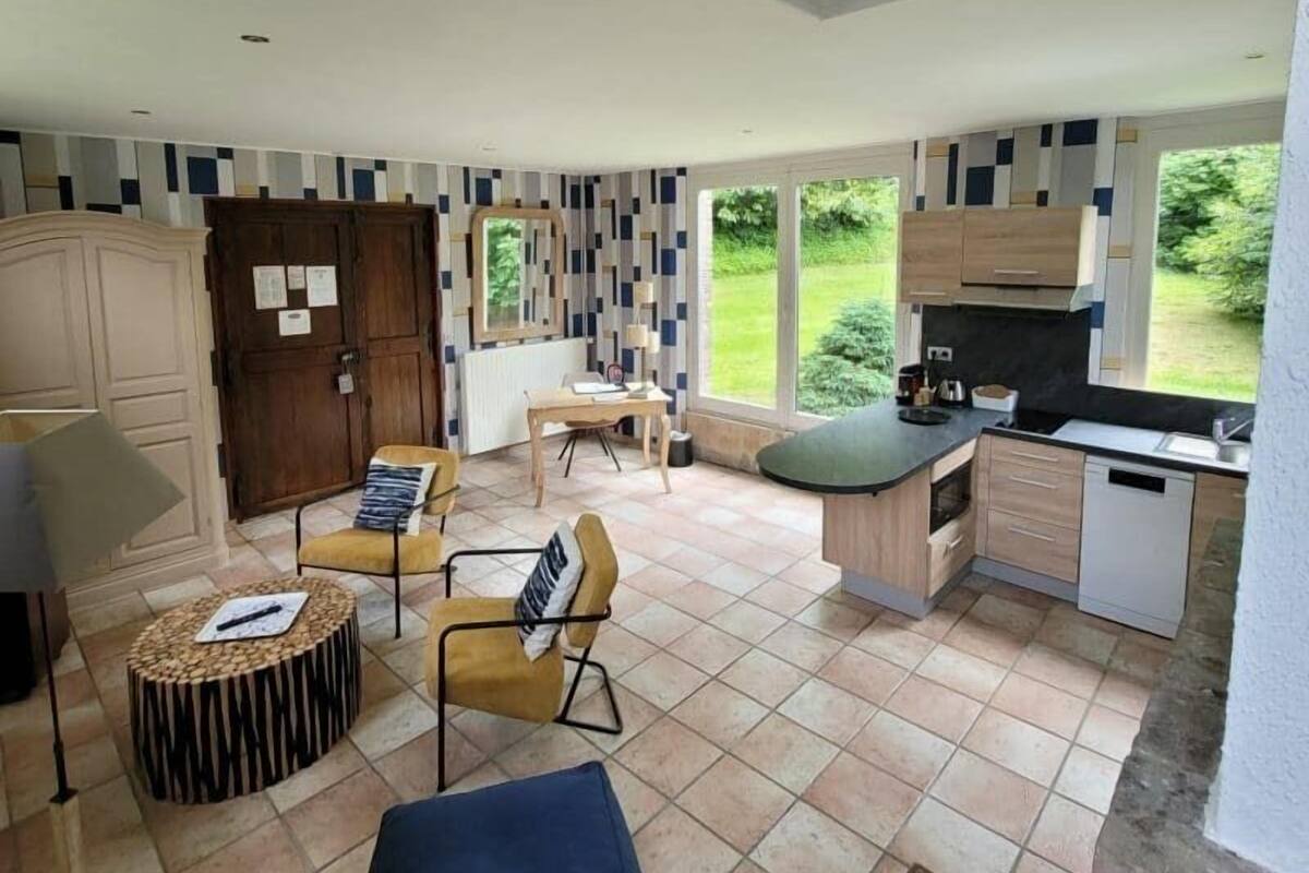A spacious living area with a high ceiling, a dining table, and a kitchen with a large window.