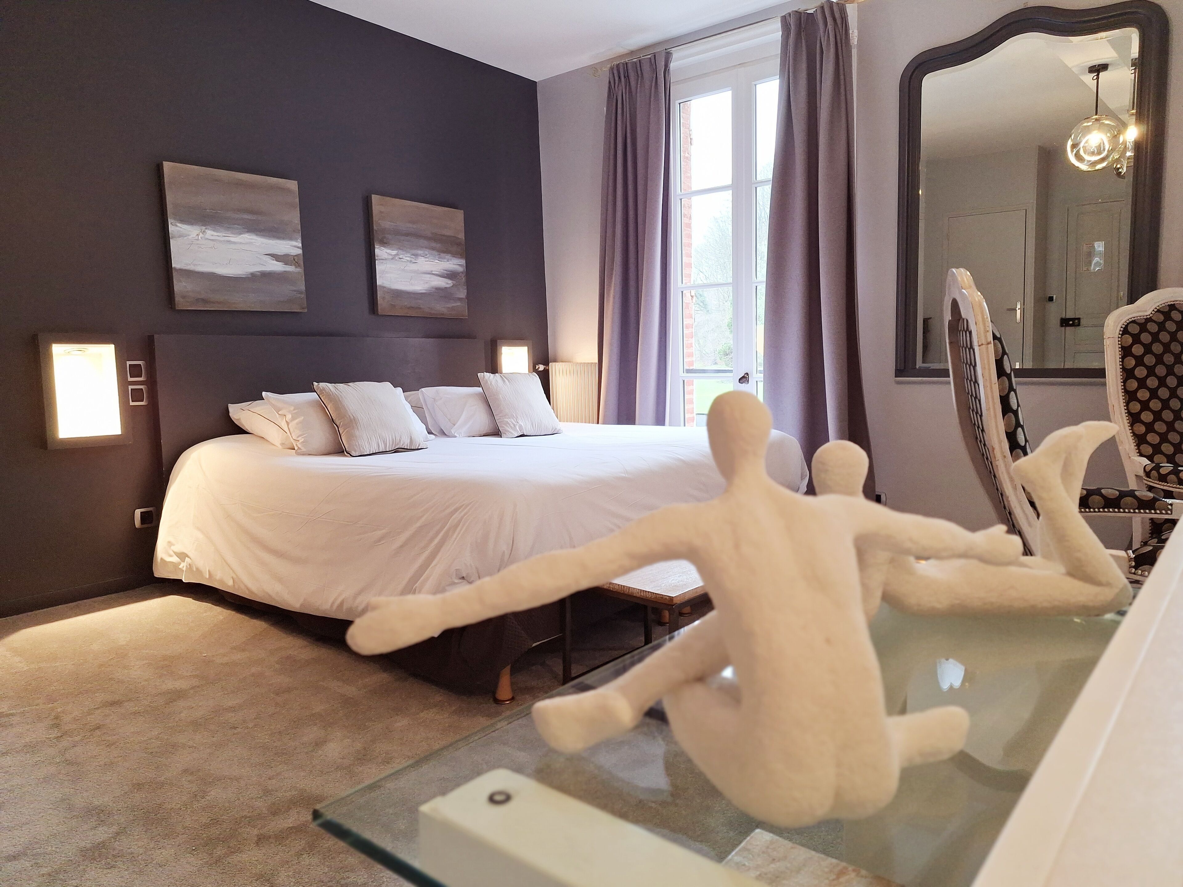 Un dormitorio con una cama grande, una mesa de vidrio y un espejo.
