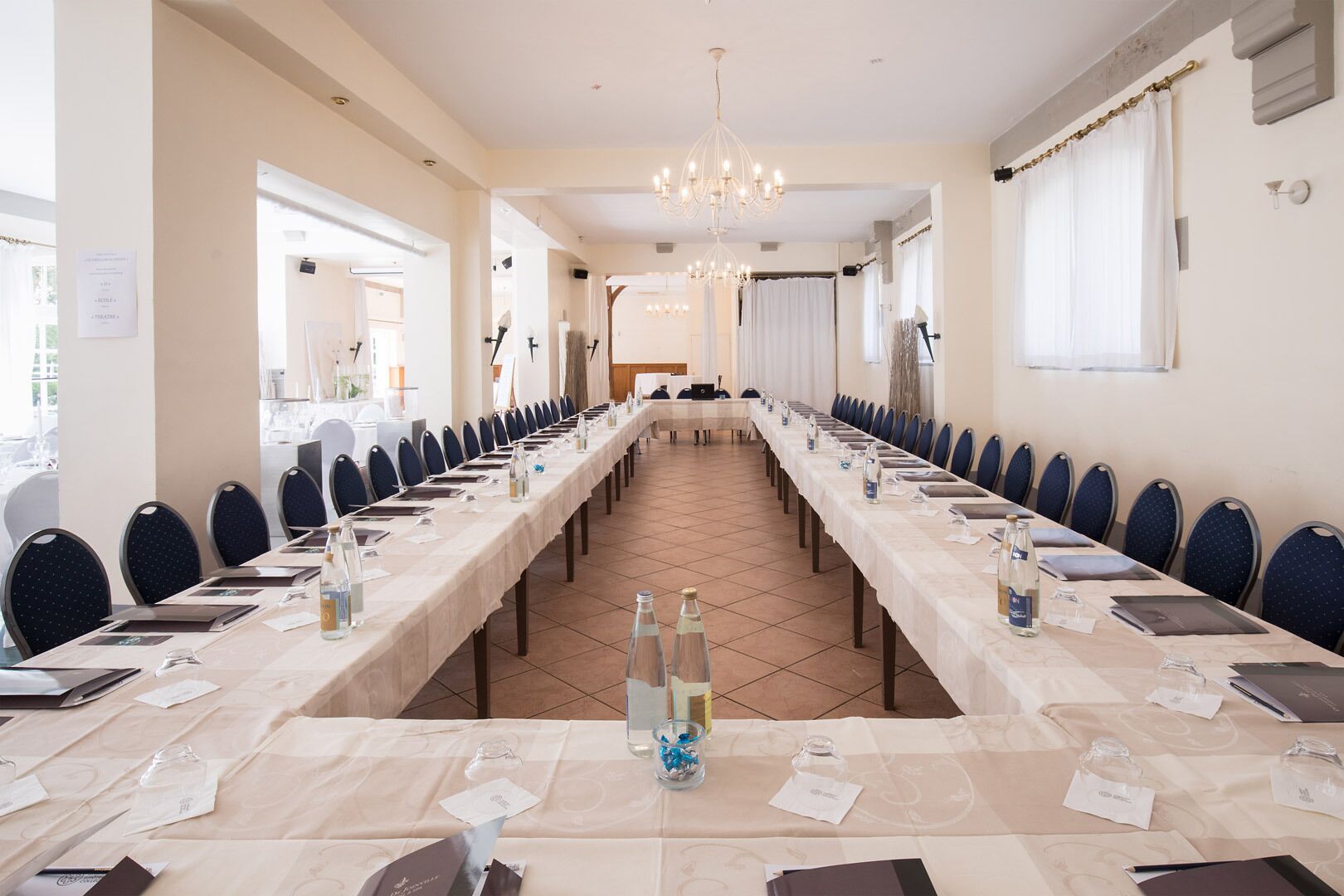 Un salón de conferencias con mesas largas, sillas y un candelabro.