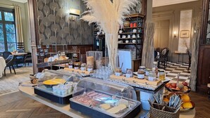 A buffet setup with various food items and a decorative plant. - Domaine de Joinville & Spa (Eu)