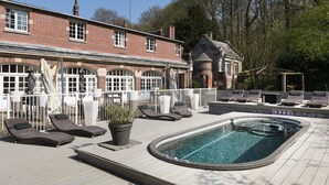 A rooftop pool area with lounge chairs, a swimming pool, and a brick building with arched windows. - Domaine de Joinville & Spa (Eu)