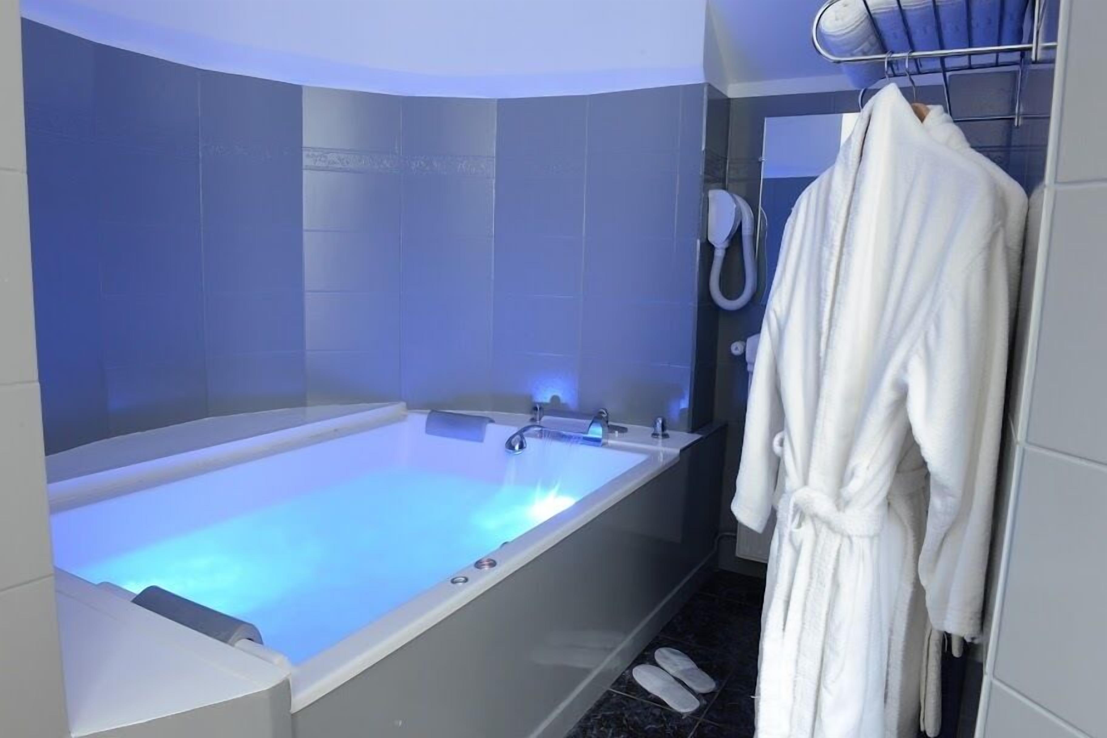 A modern bathroom with a large bathtub, a towel rack, and a shower head.