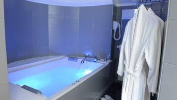 A modern bathroom with a large bathtub, a towel rack, and a shower head.