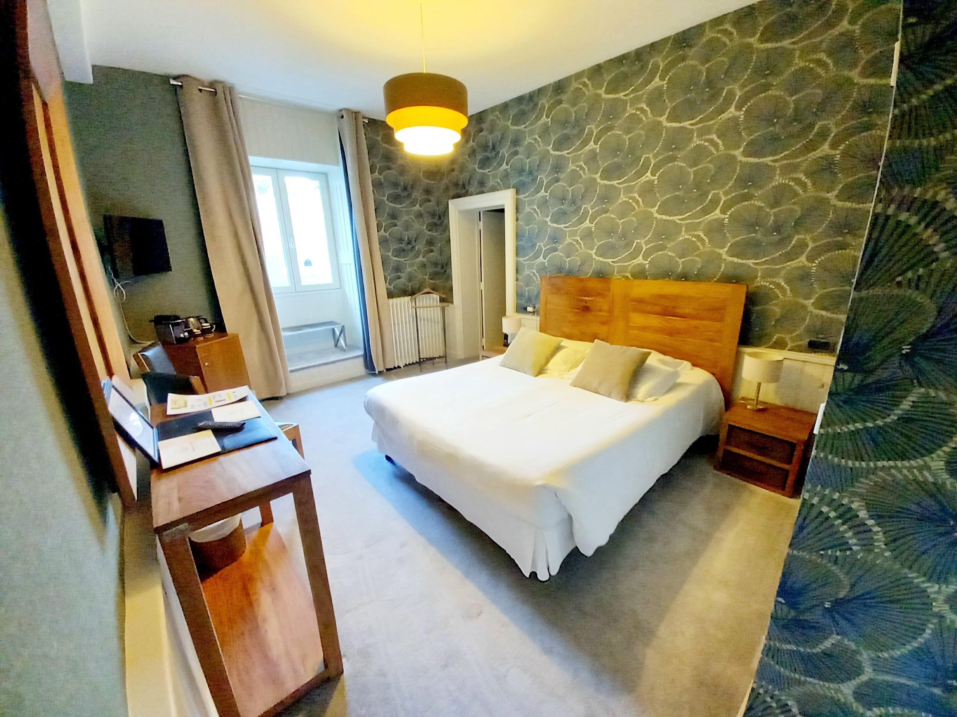 Habitación de hotel con una cama grande, un escritorio, una silla, un espejo y una pared con diseño de piedra.