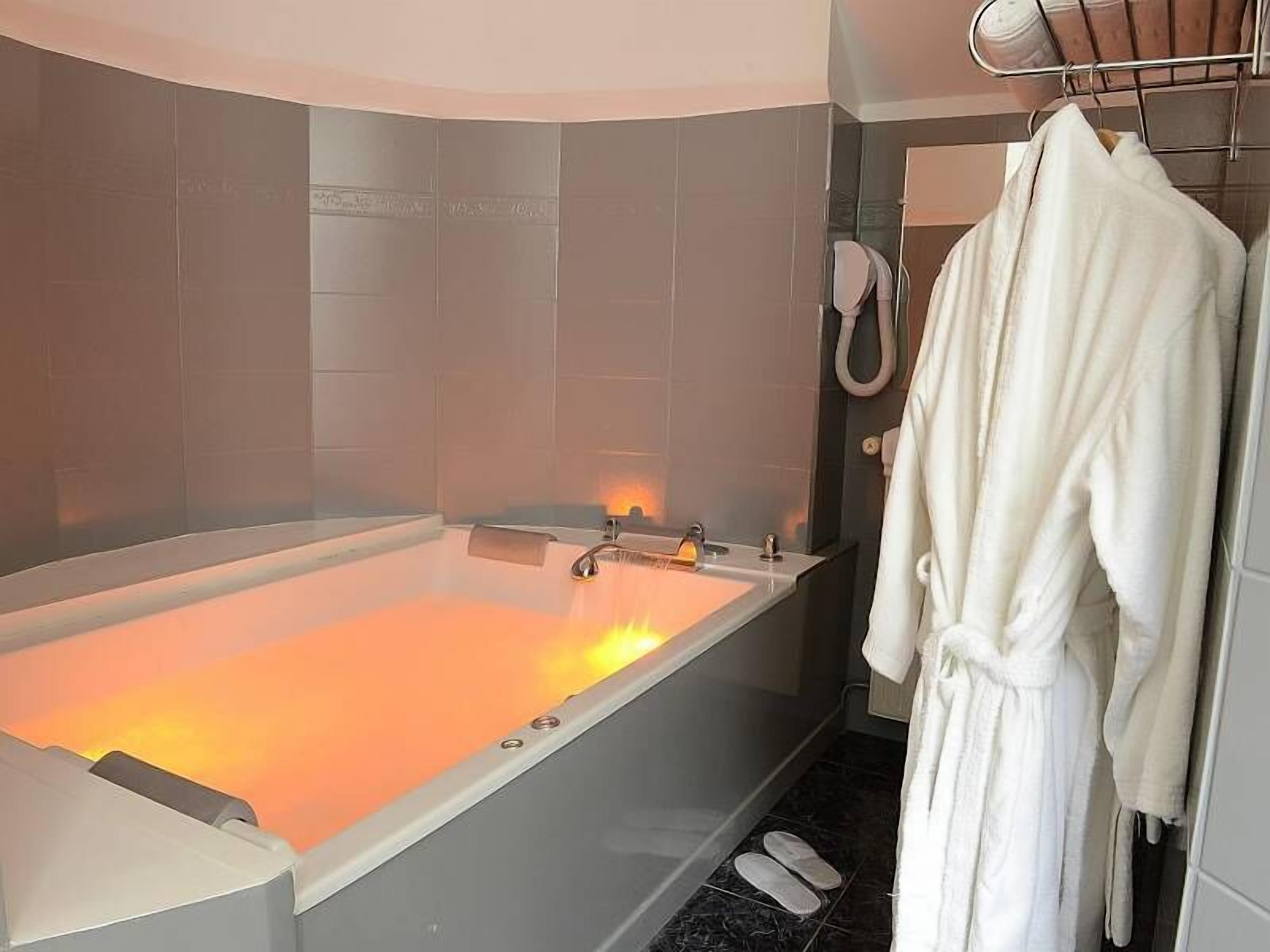 Une salle de bain moderne avec une grande baignoire, un porte-serviettes avec un peignoir, et un espace douche.