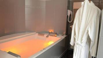 Une salle de bain moderne avec une grande baignoire, un porte-serviettes avec un peignoir, et un espace douche.