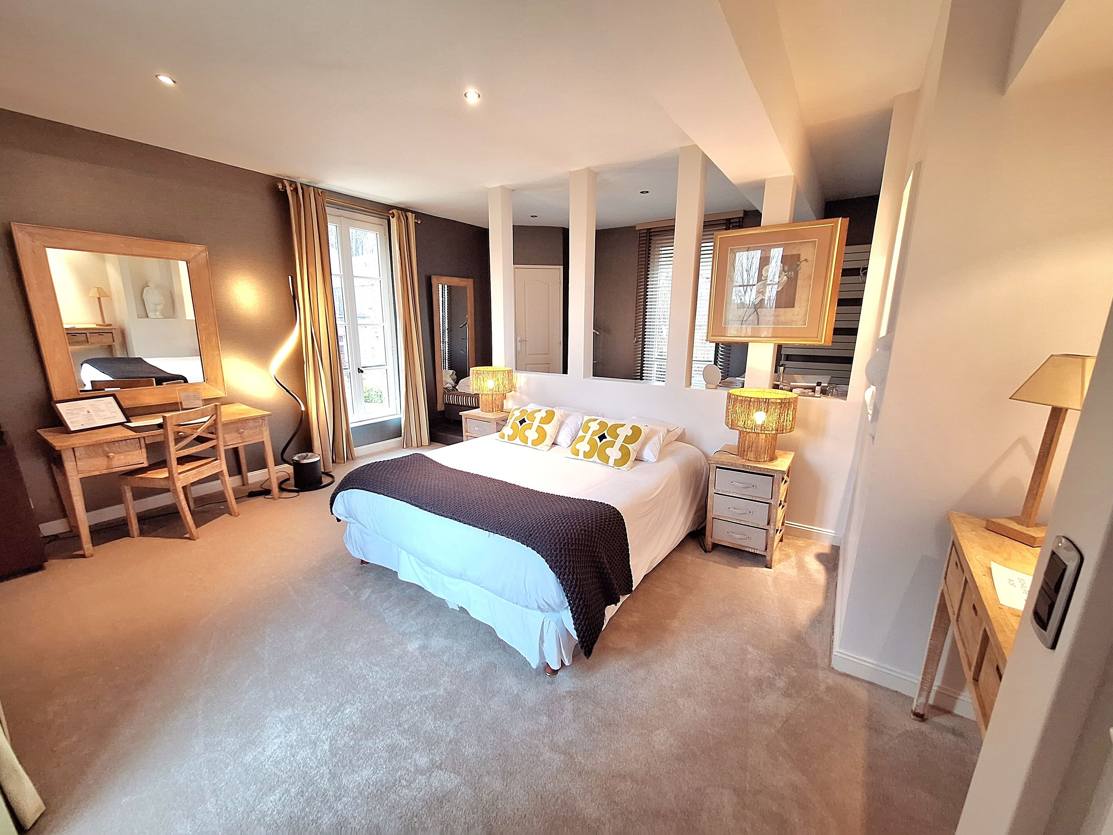 Une chambre spacieuse avec un grand lit, un bureau et une chaise. Il y a deux tables de chevet avec des lampes.