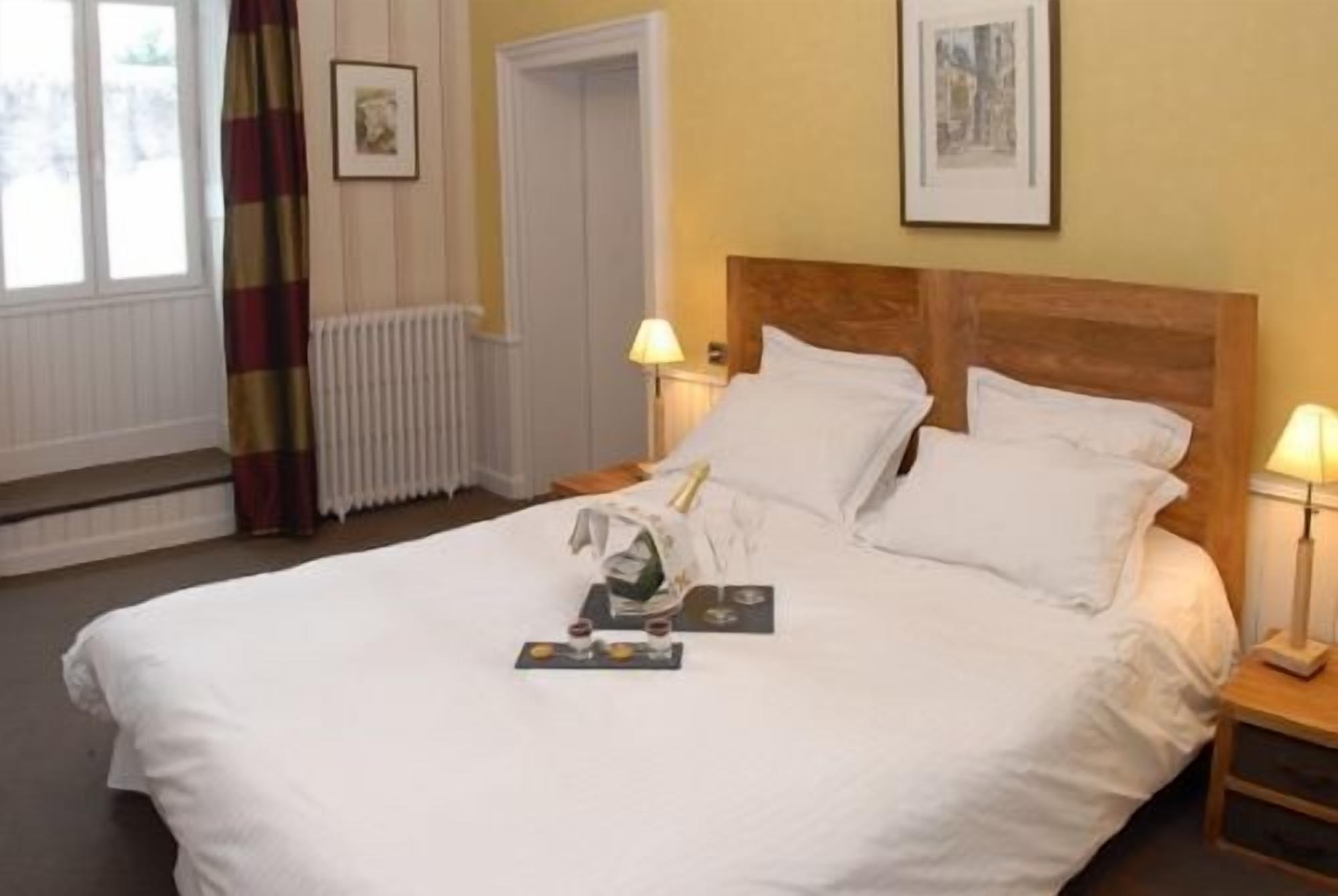 A neatly made bed with white linens, two bedside lamps, and a framed picture on the wall.