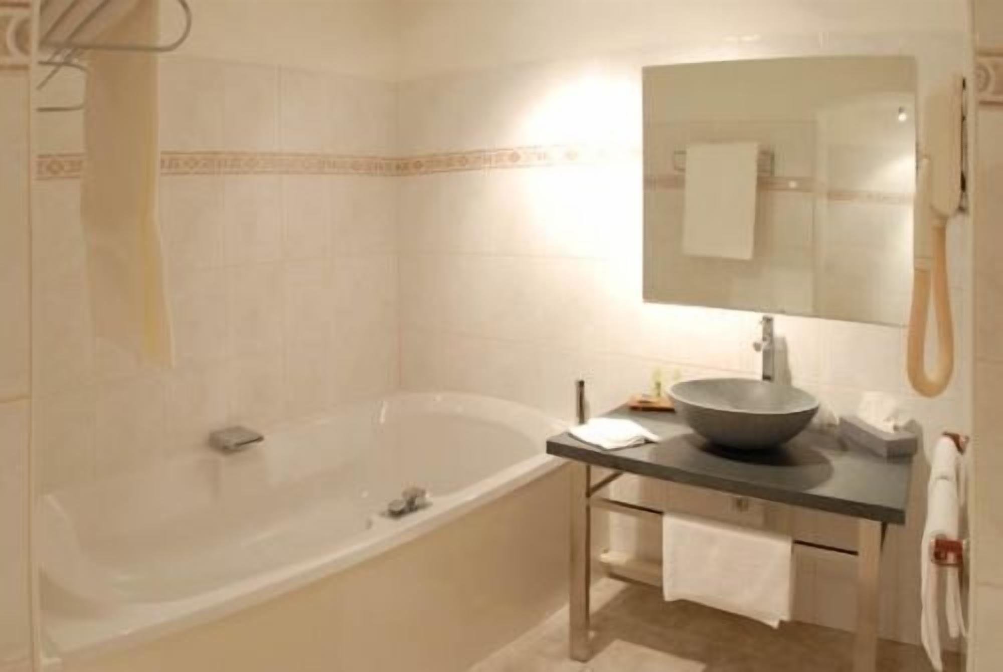 Une salle de bain avec une baignoire, un lavabo sur colonne et un porte-serviettes.