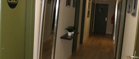 A hallway with wooden flooring, green doors, and a number sign on one door.