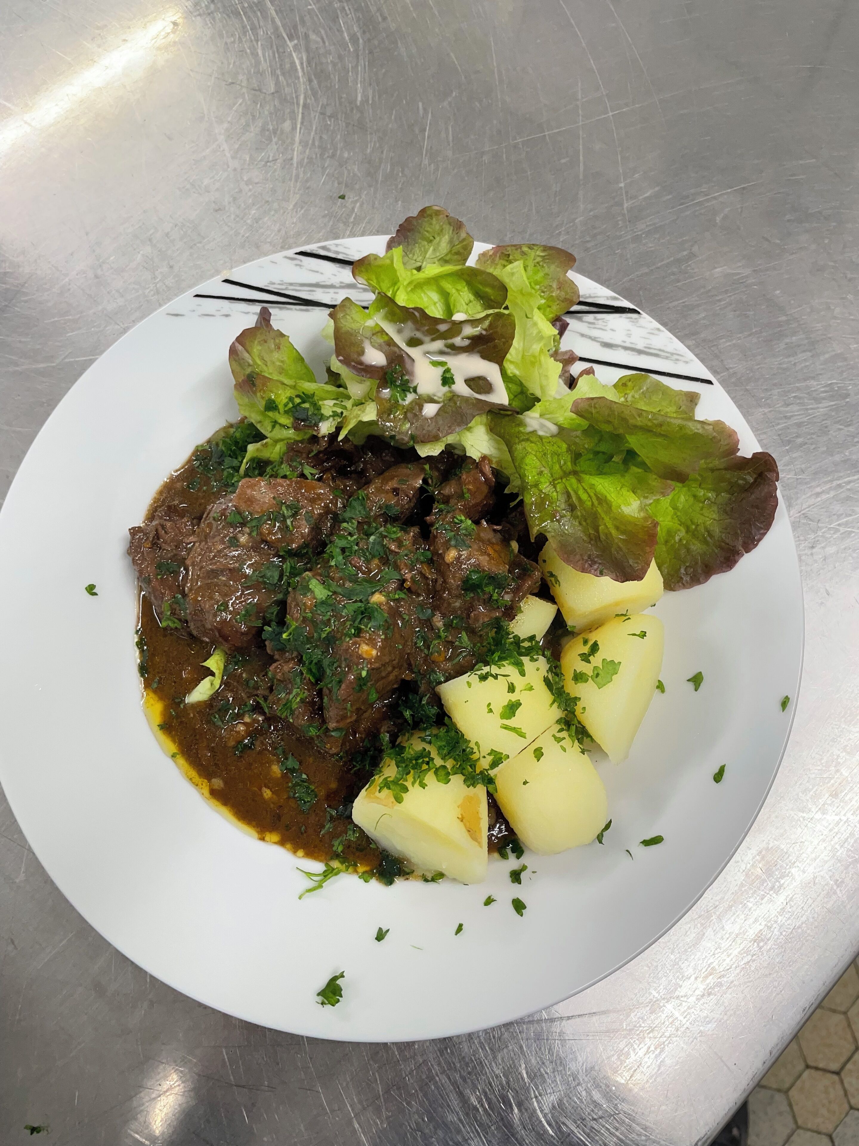 Un plato de comida con carne, patatas y lechuga.