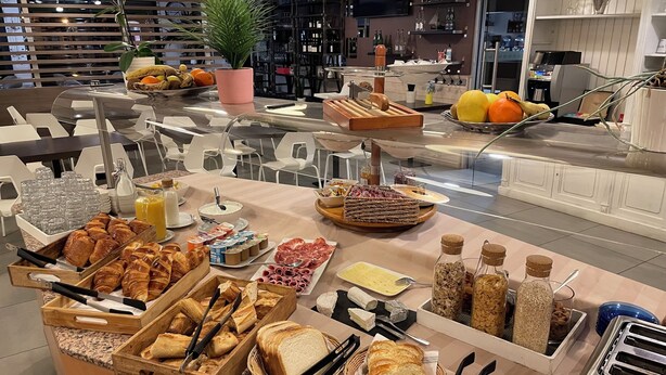 Un bufé con diversas opciones de comida, incluyendo pan, pasteles y frutas.