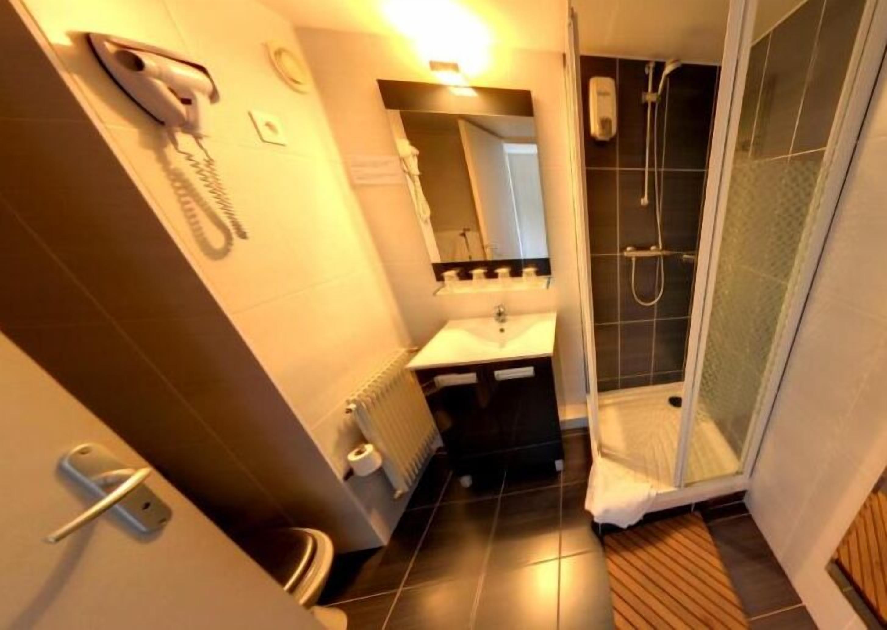 A modern bathroom with a shower, a hairdryer, and a sink.