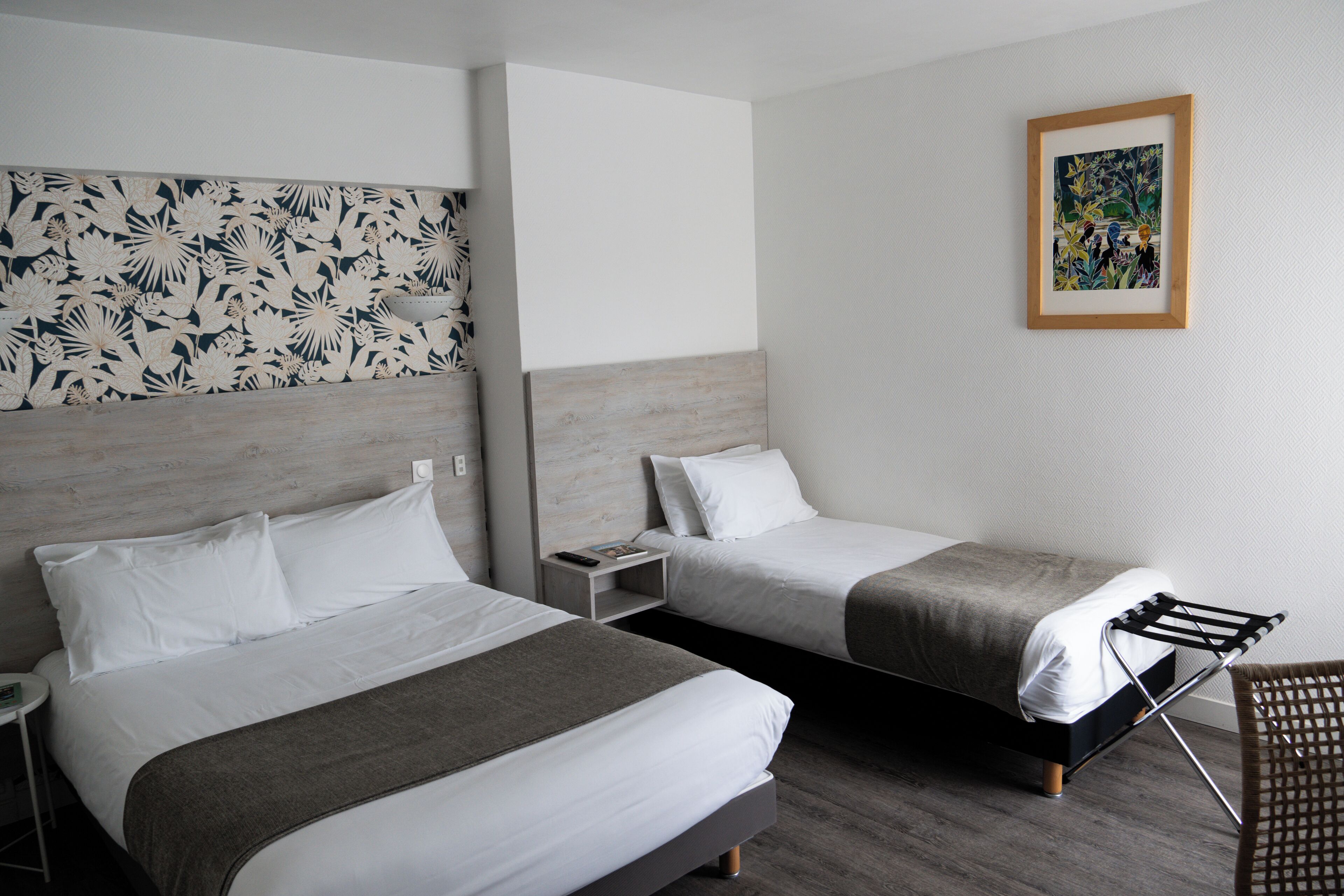 Une chambre d’hôtel avec deux lits, une œuvre d’art accrochée au mur et une chaise.