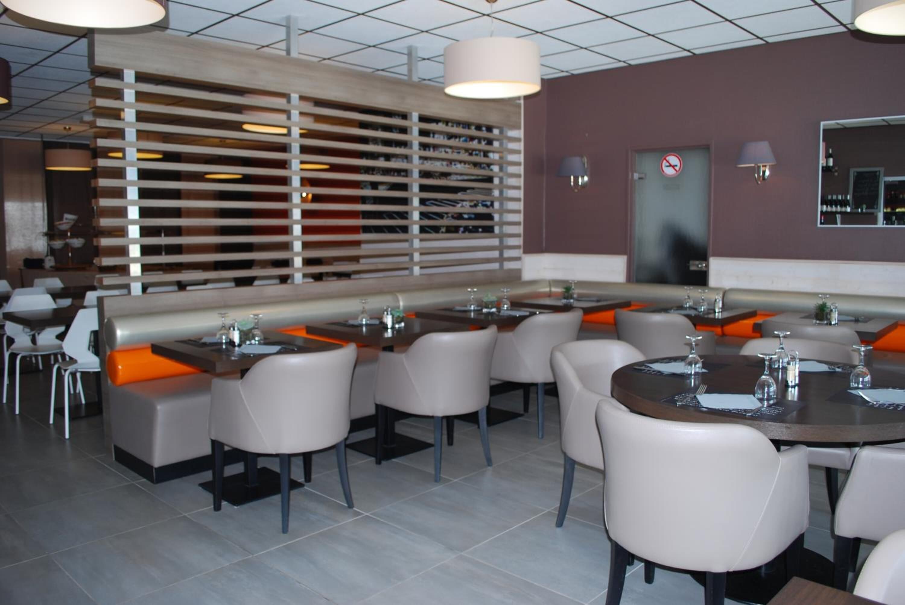 A modern restaurant with high tables and booths, a large wall with a wine rack, and a no-smoking sign.