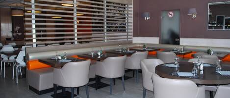 A modern restaurant with high tables and booths, a large wall with a wine rack, and a no-smoking sign.