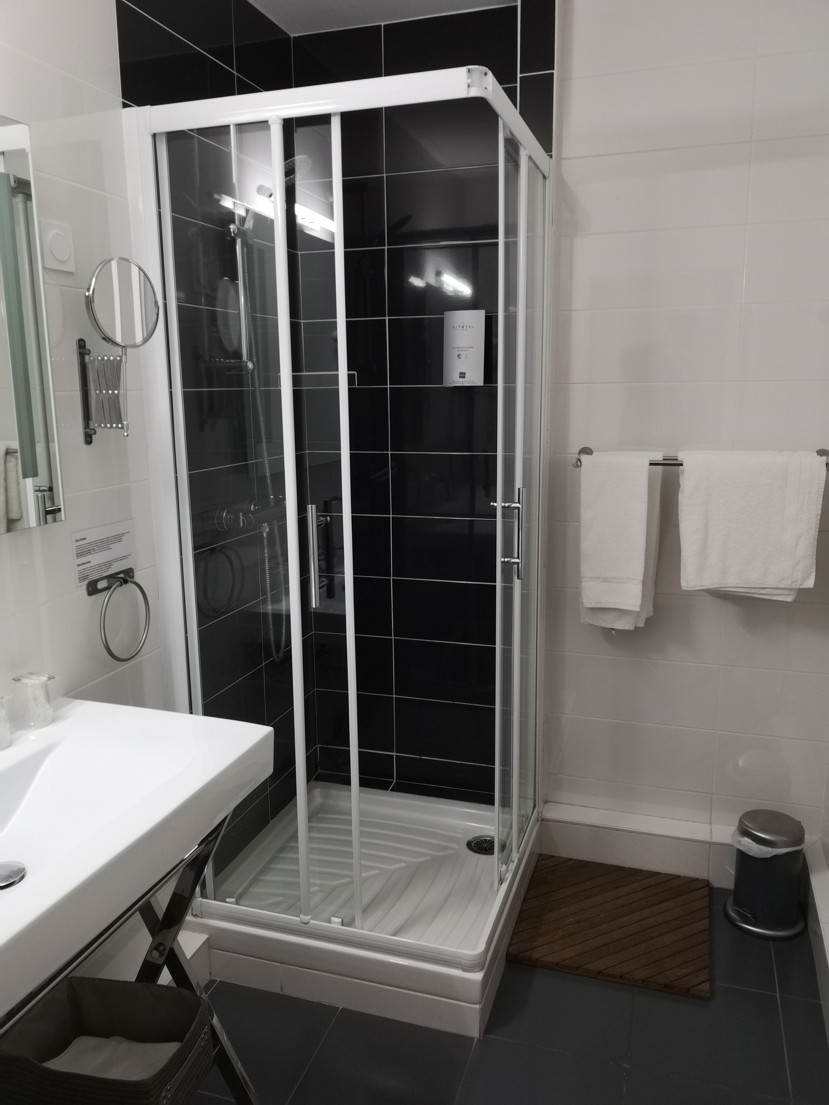 Un baño moderno con ducha de vidrio, lavabo blanco y un perchero para toallas.