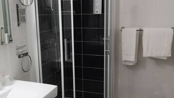 Un baño moderno con ducha de vidrio, lavabo blanco y un perchero para toallas.