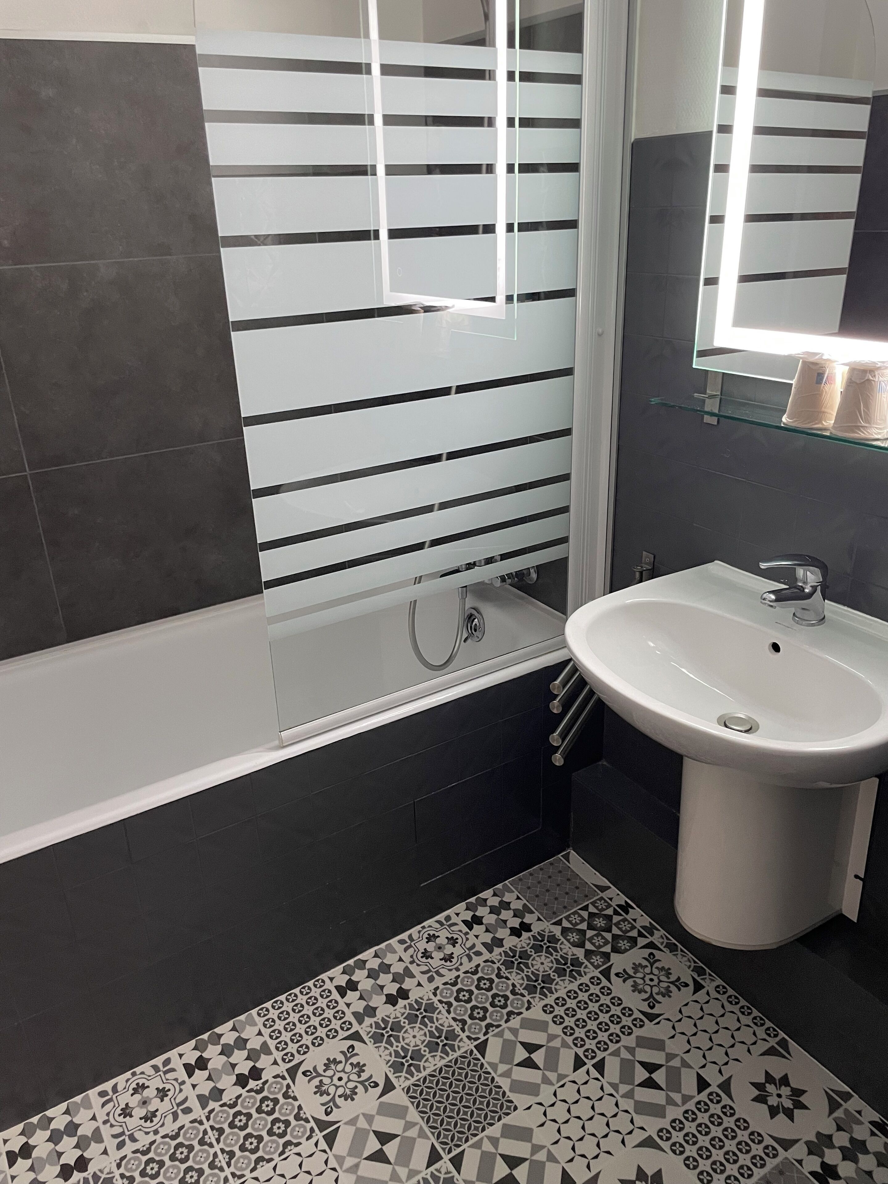 Un baño moderno con bañera, lavamanos y espejo.