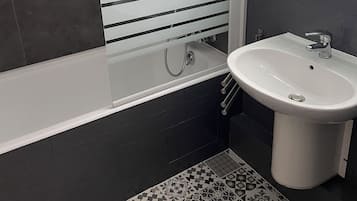 Un baño moderno con bañera, lavamanos y espejo.