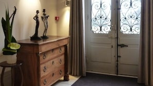 A room with a wooden dresser, a potted plant, and a door with decorative ironwork.