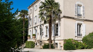 A large, two-story building with a symmetrical facade, white shutters, and a central entrance with steps.