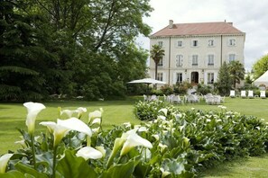 A large, elegant building with a red-tiled roof and white shutters, surrounded by lush greenery and a well-maintained lawn. - Teritoria - Domaine de Clairefontaine (Chonas-l'Amballan)