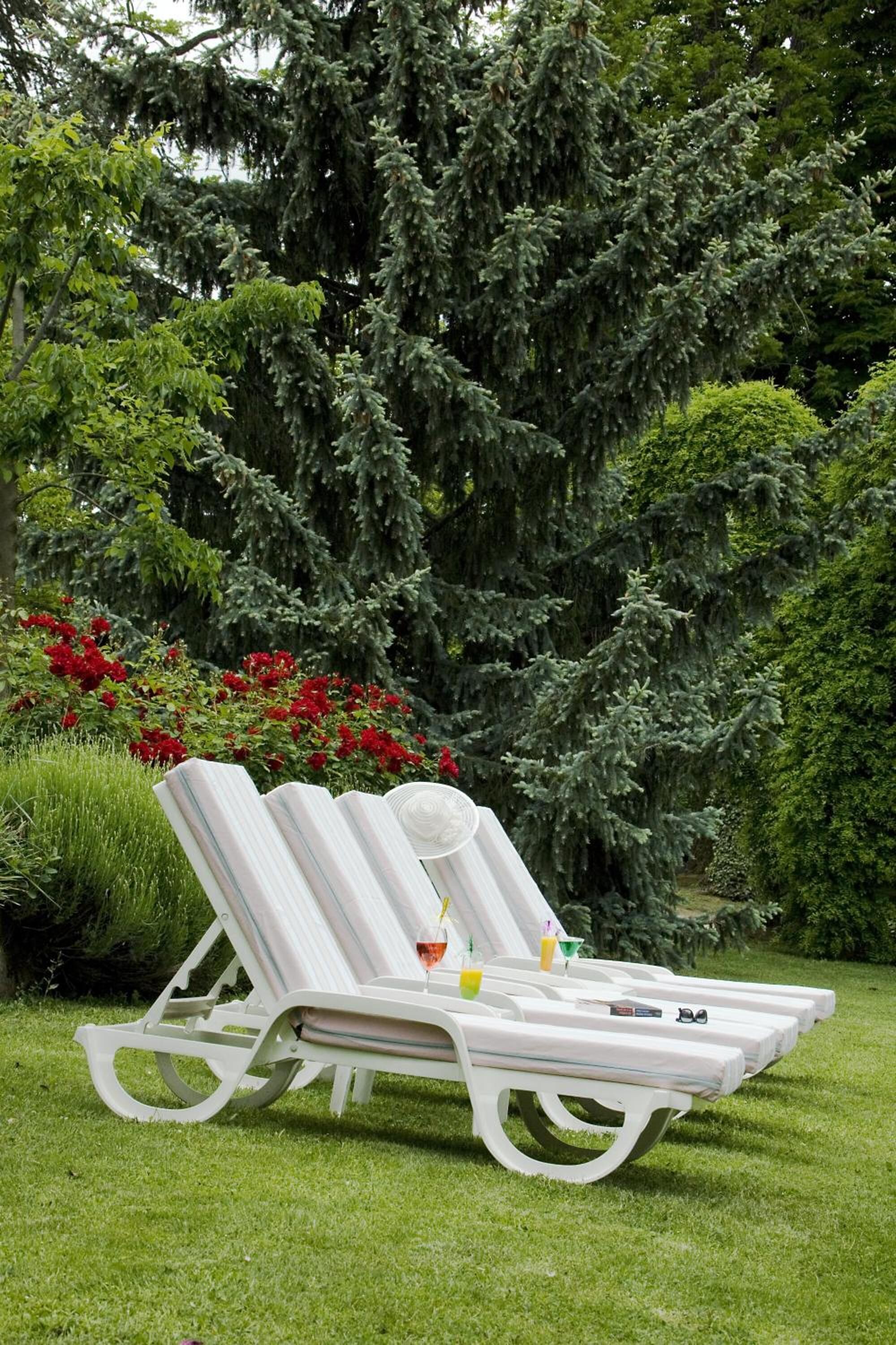 Un fauteuil de relaxation blanc, doté d’un plateau en verre, placé sur une pelouse verdoyante.