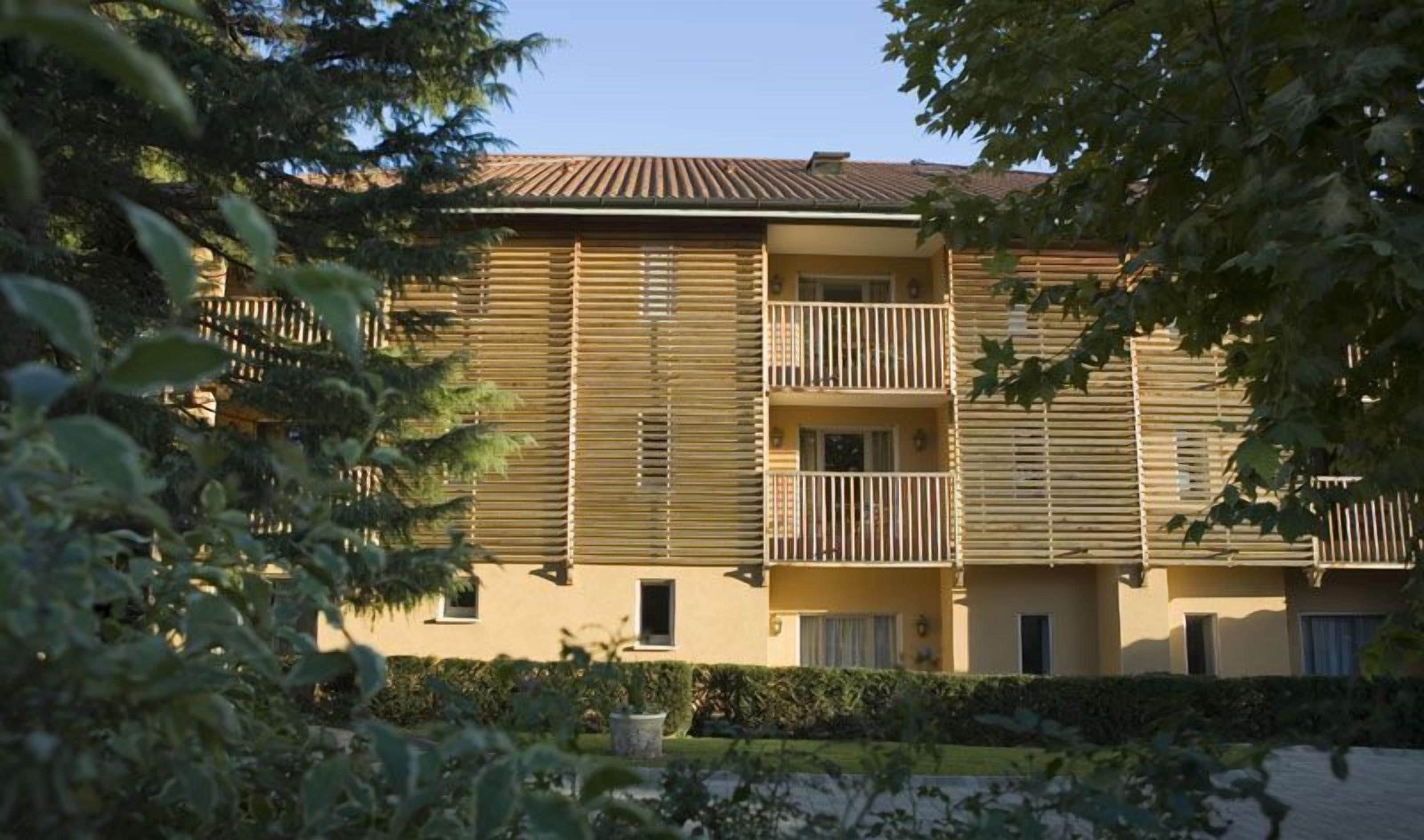 A multi-story building with horizontal wooden slats on the facade, balconies with railings, and a flat roof.