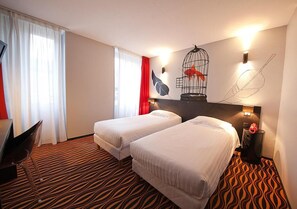 Habitación de hotel con dos camas, un escritorio y una silla.