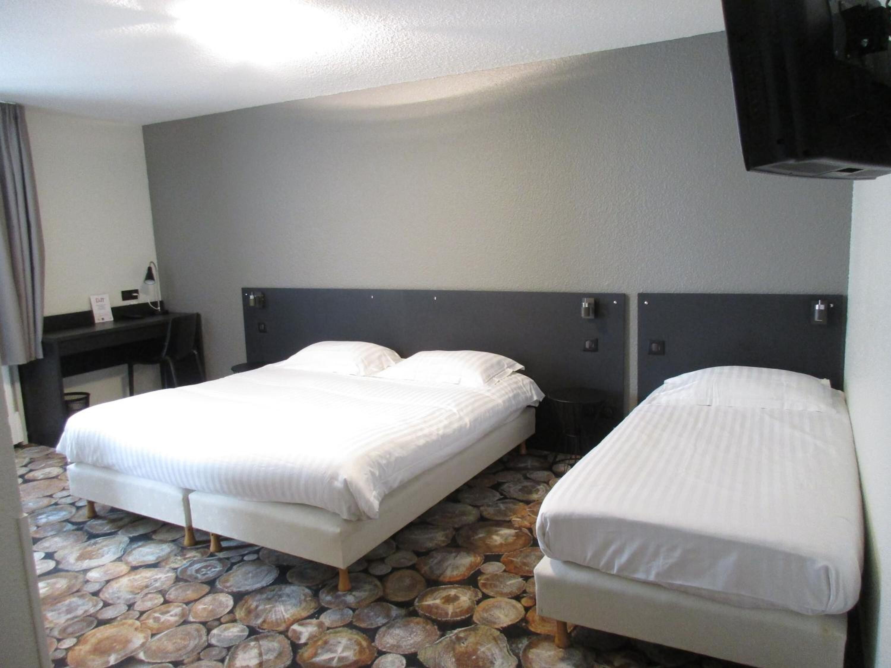 Une chambre d’hôtel avec deux lits, un bureau et une télévision.