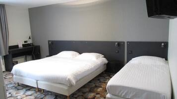 A hotel room with two beds, a desk, and a television.