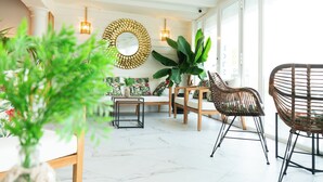 A spacious living area with a white ceiling, wooden furniture, and large windows. - Hotel Don Diego (Suances)