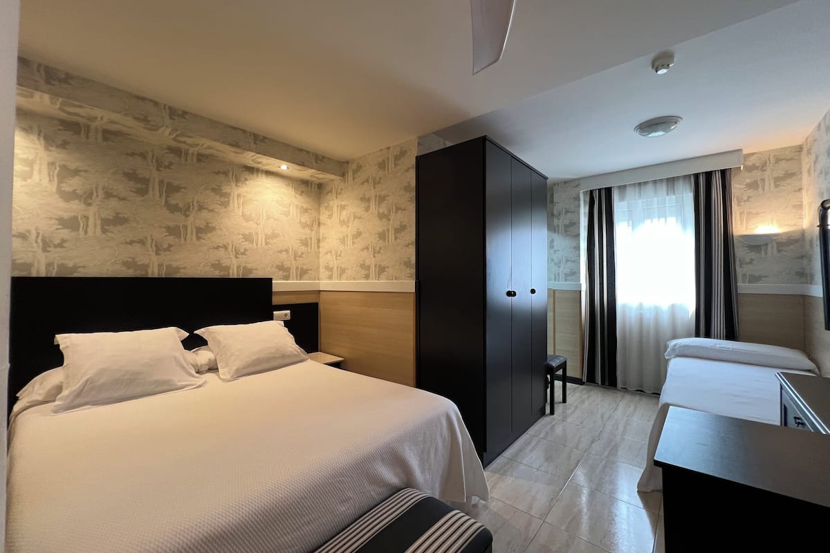 A hotel room with a large bed, a desk, and a wardrobe.