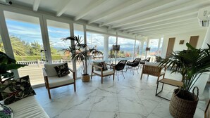 A spacious patio with white furniture, potted plants, and a view of the cityscape. - Hotel Don Diego (Suances)