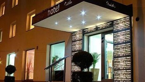 Fachada de hotel con un letrero, una escalera y buena iluminación.