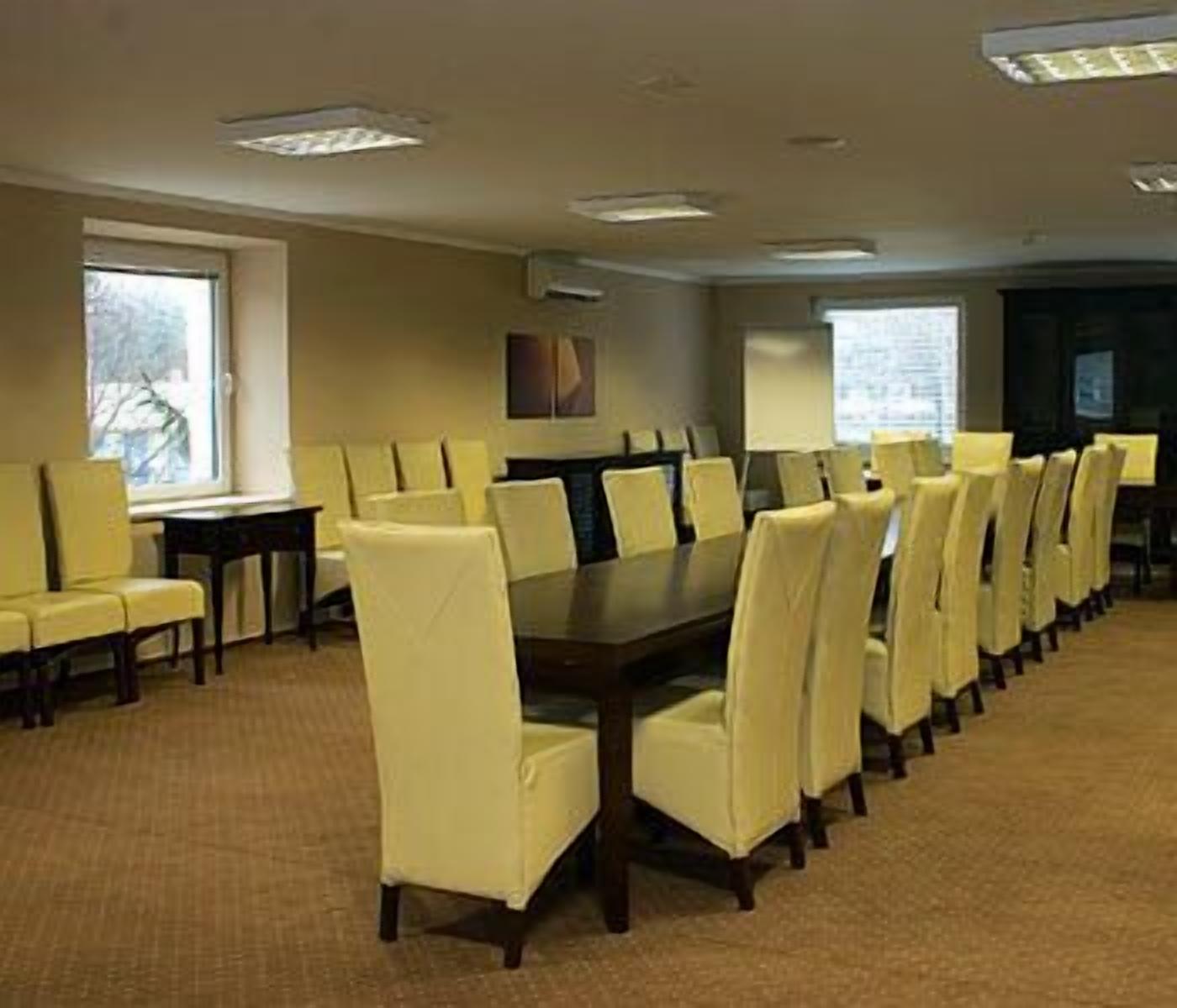 A conference room with a long table and chairs, large windows, and a carpeted floor.
