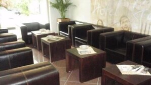 Un hall de hotel con asientos de cuero, mesas de madera y una planta grande.
