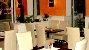 Un restaurante con una pared naranja cálida, sillas blancas y una mesa con un menú.
