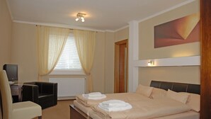 Una habitación de hotel con cama, escritorio con silla, televisión y ventana con cortinas.